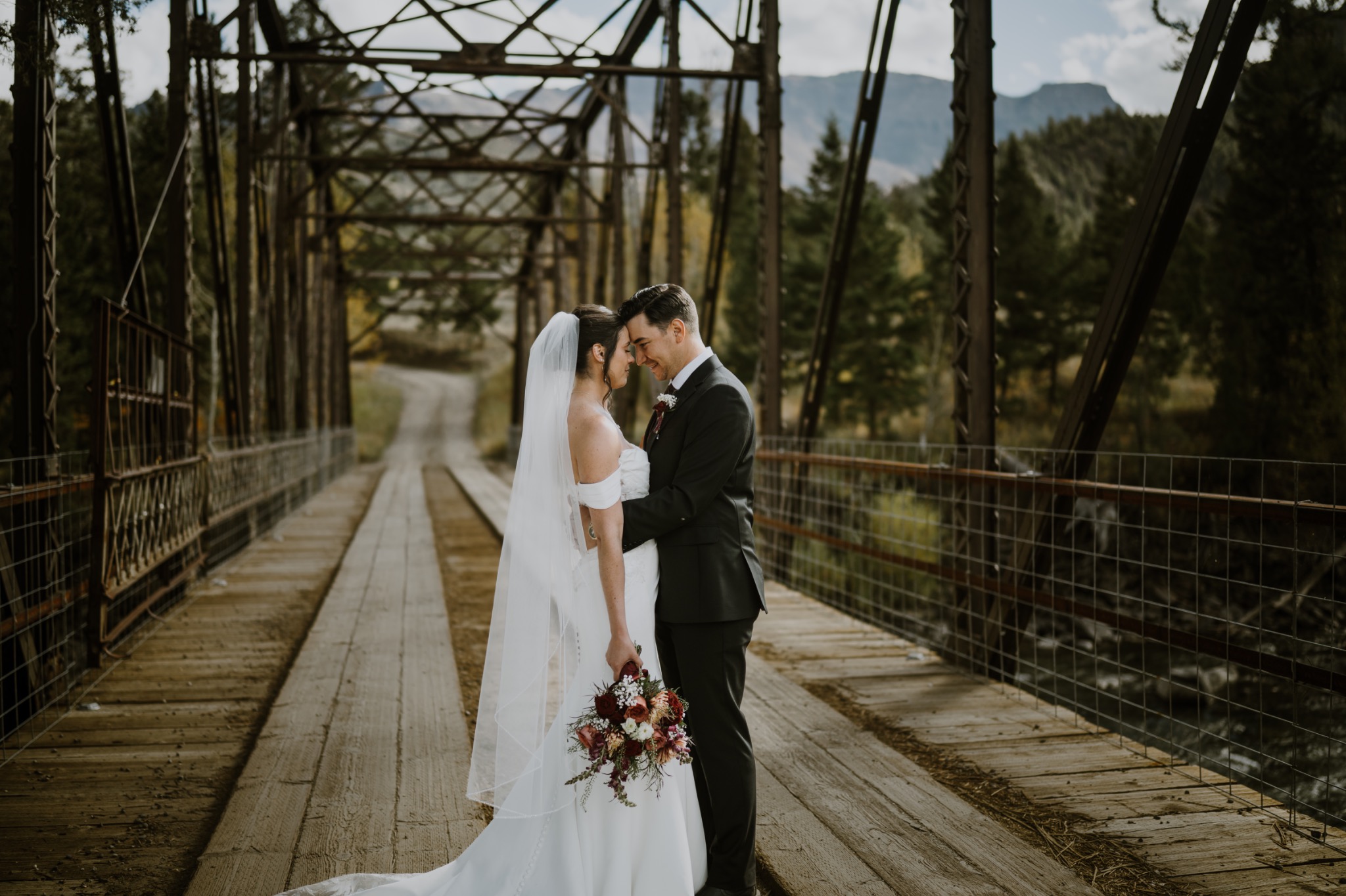 Bride and groom embracing at the center of a rustic bridge