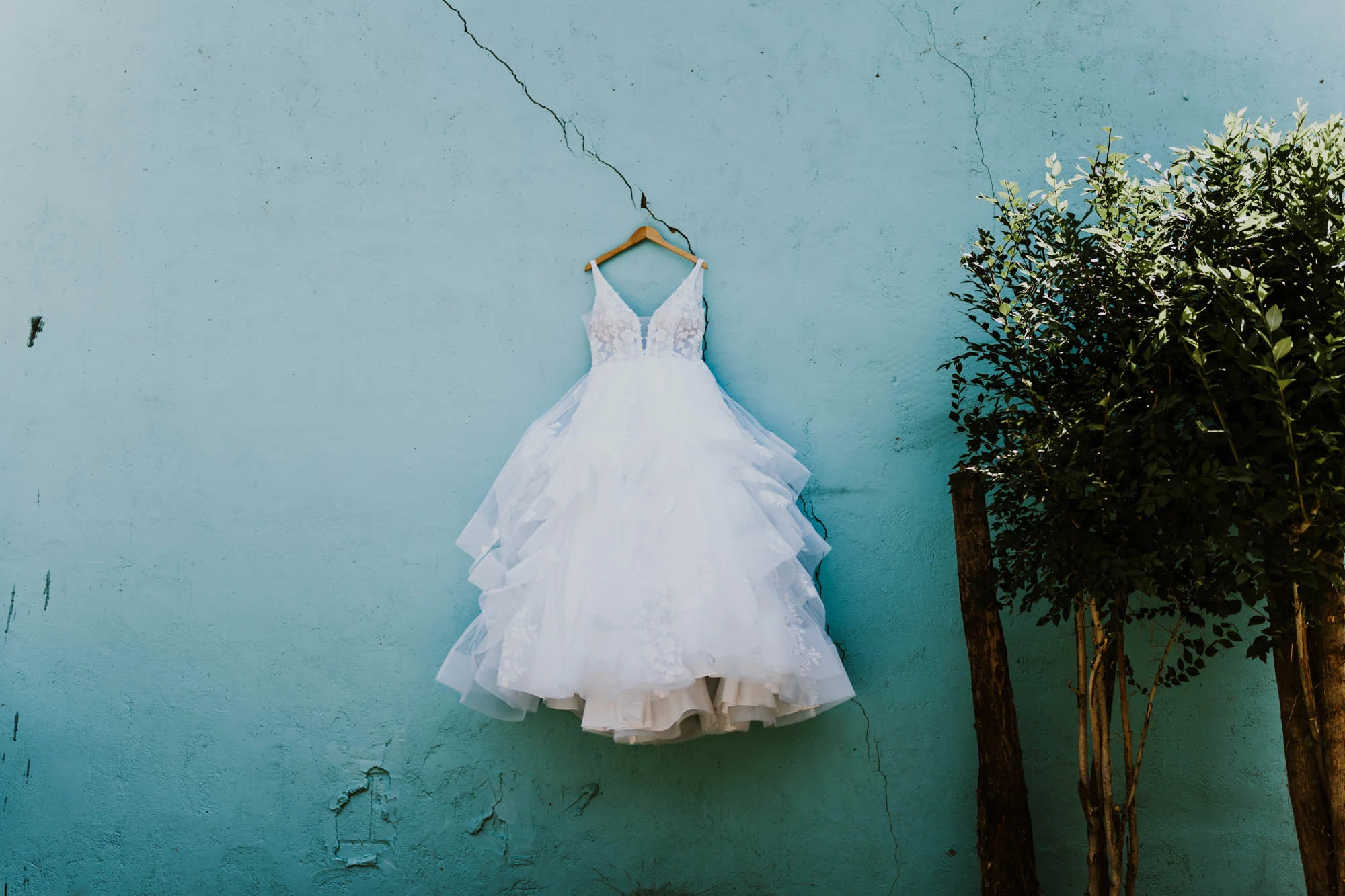 Wedding dress hanging against a turquoise wall
