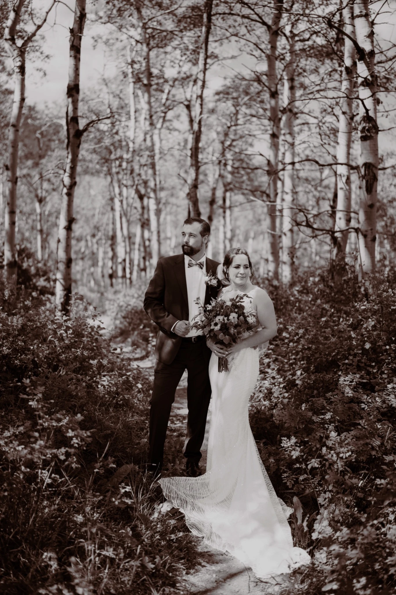 Black-and-white bridal couple portrait among slender trees