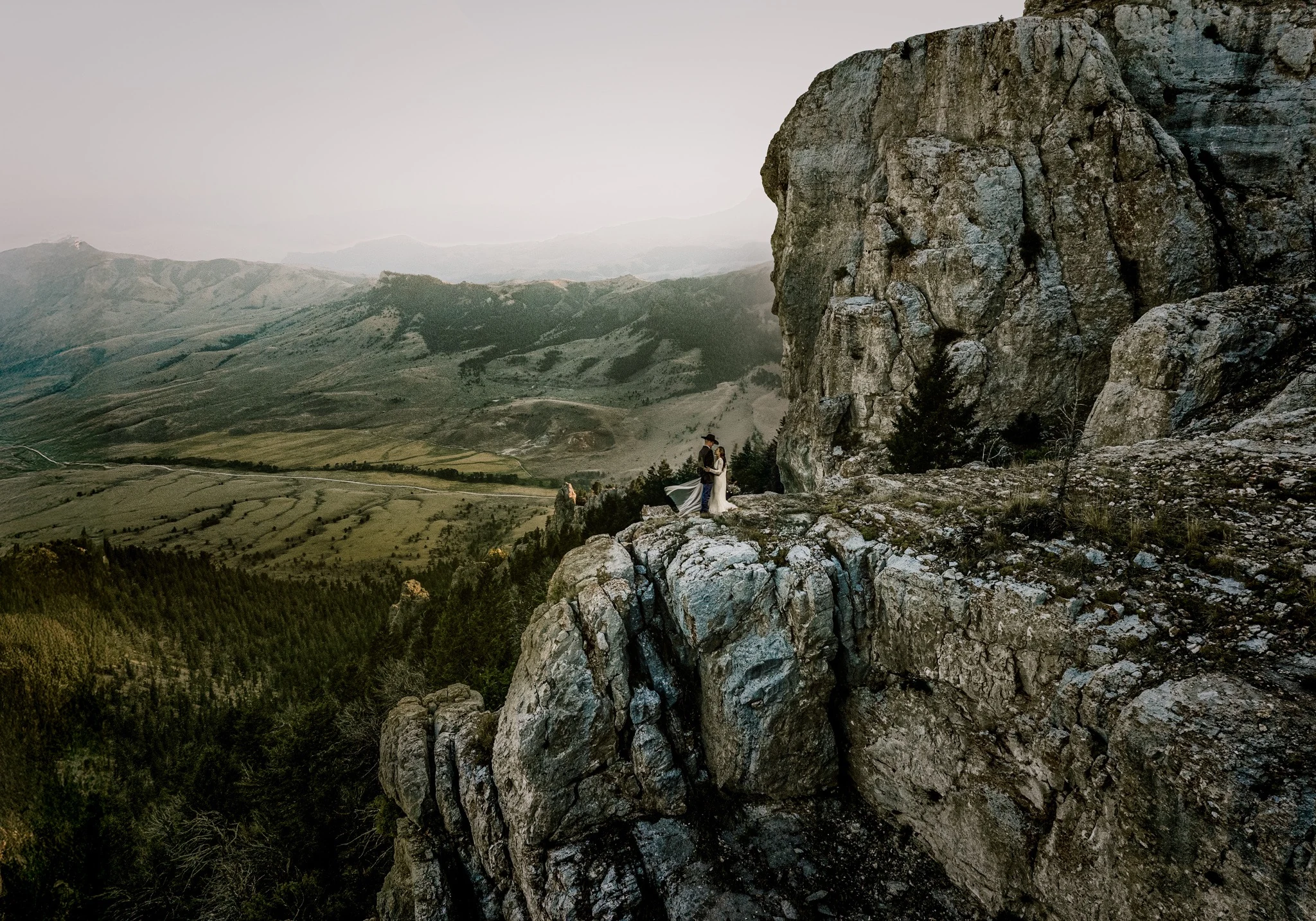Wedding couple on a rocky ledge with sweeping mountain scenery