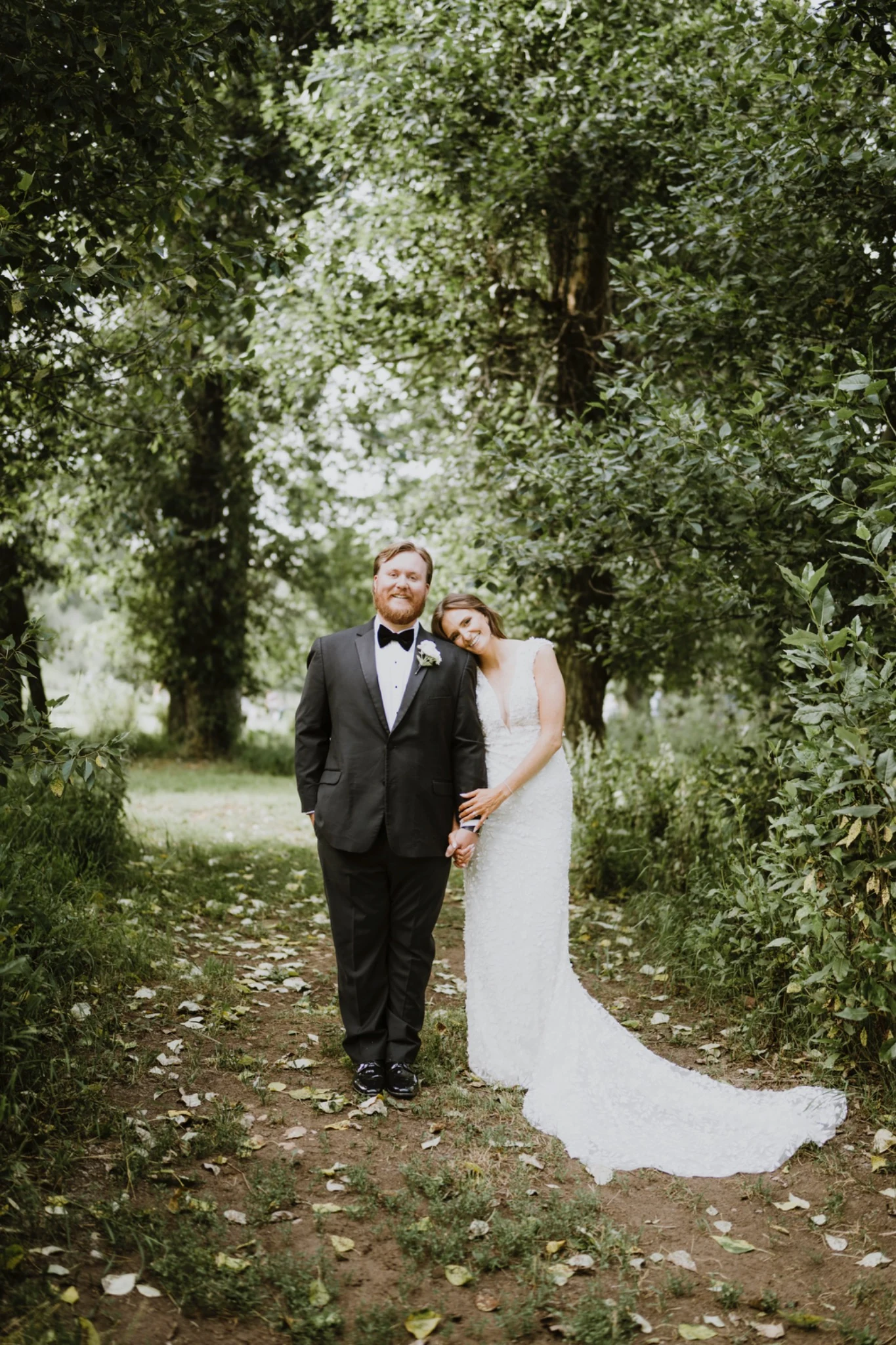 Newly married couple on a lush tree-lined path