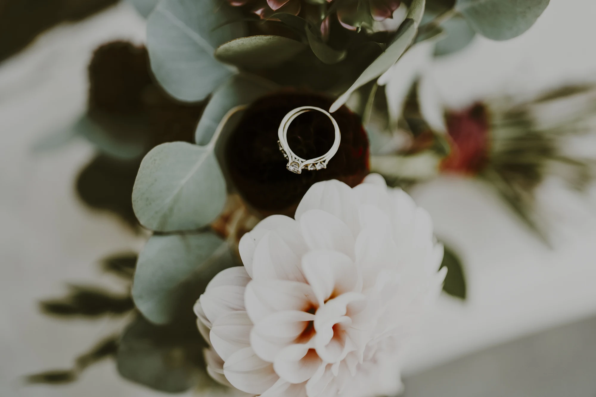 Diamond engagement ring nestled among pastel flowers and eucalyptus