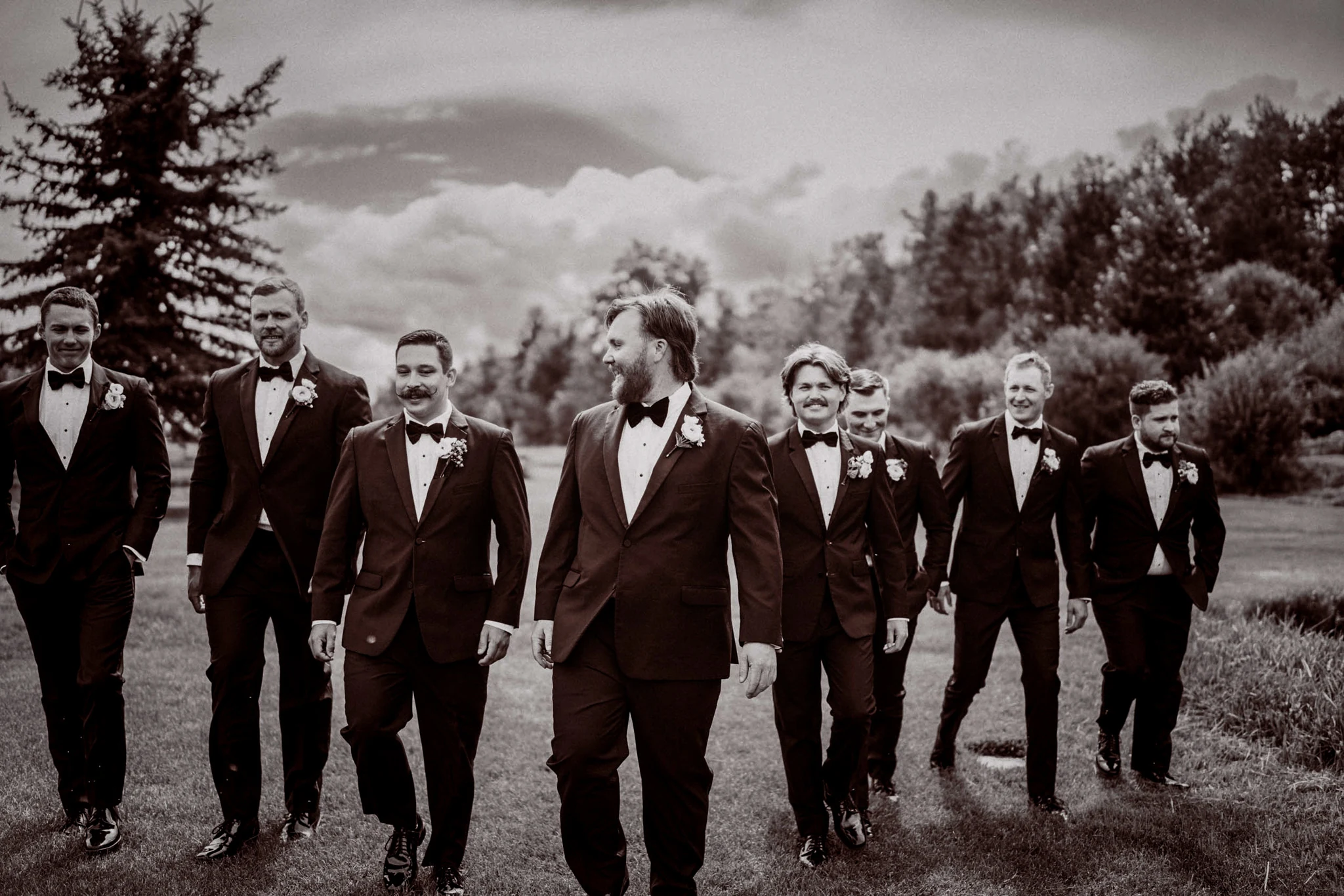 Groom walking with his groomsmen in black tuxedos