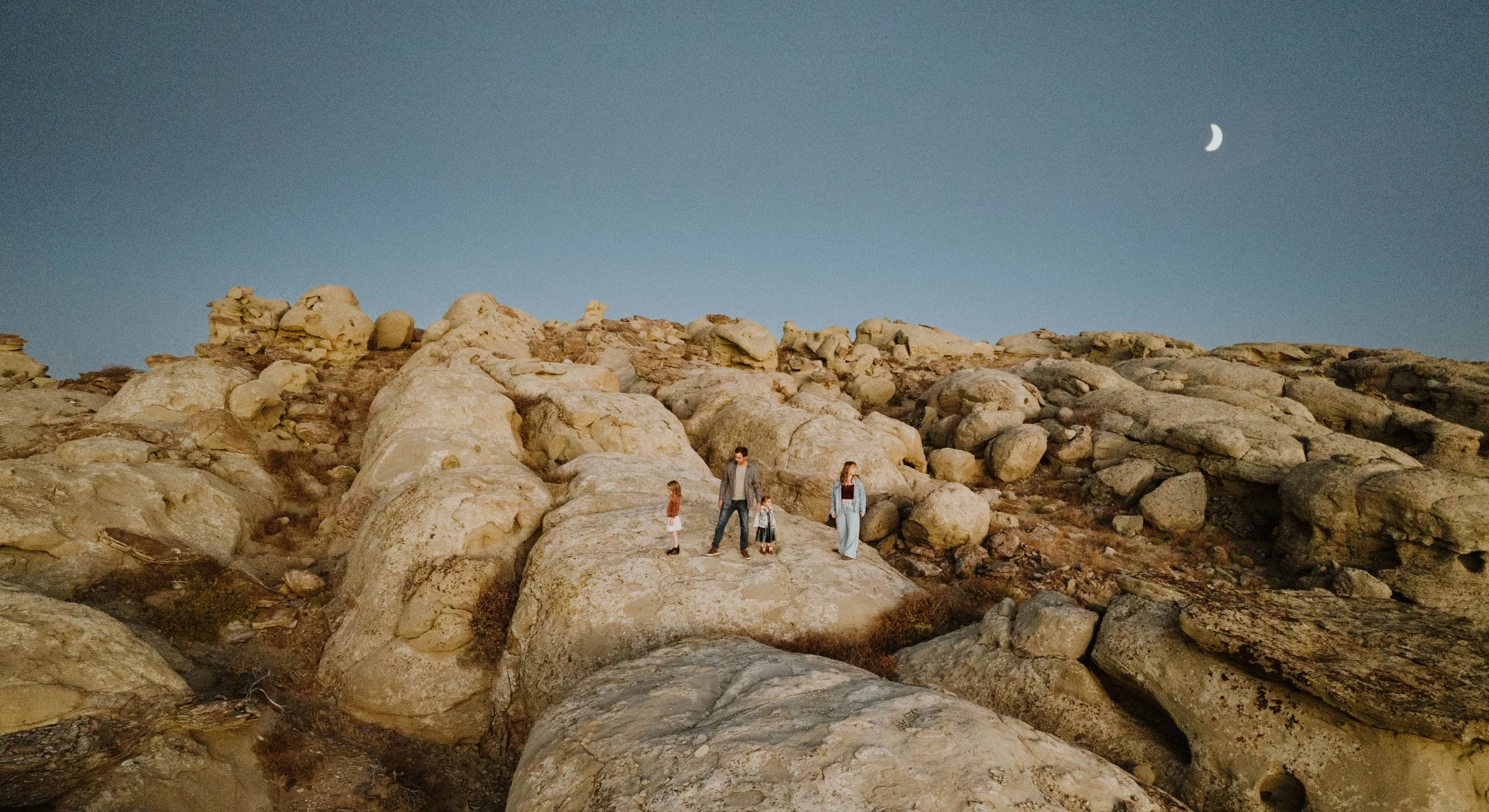 Tia and her family standing on sandstone rock formations under a crescent moon