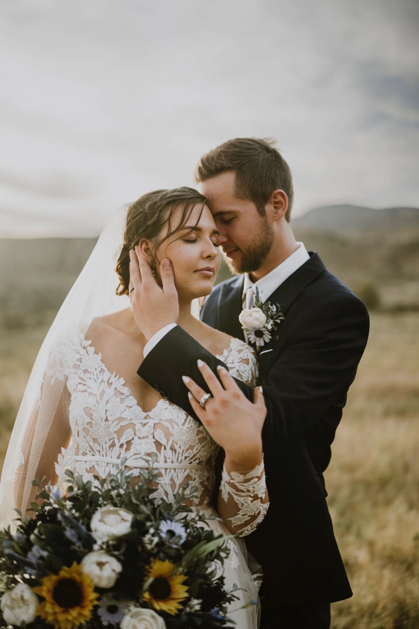 Bride and groom embracing with a sunflower wedding bouquet