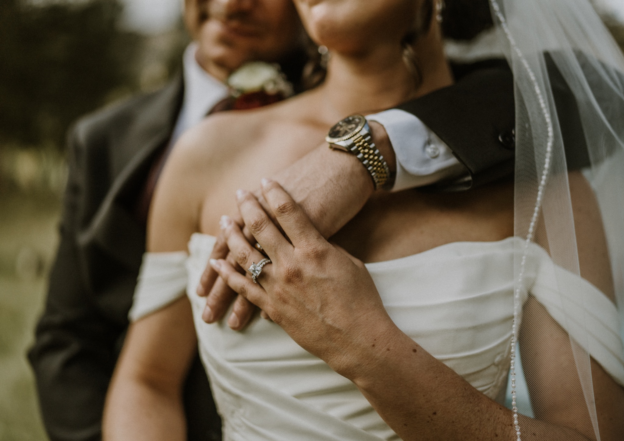 Close wedding portrait highlighting the bride's ring and the couple's embrace