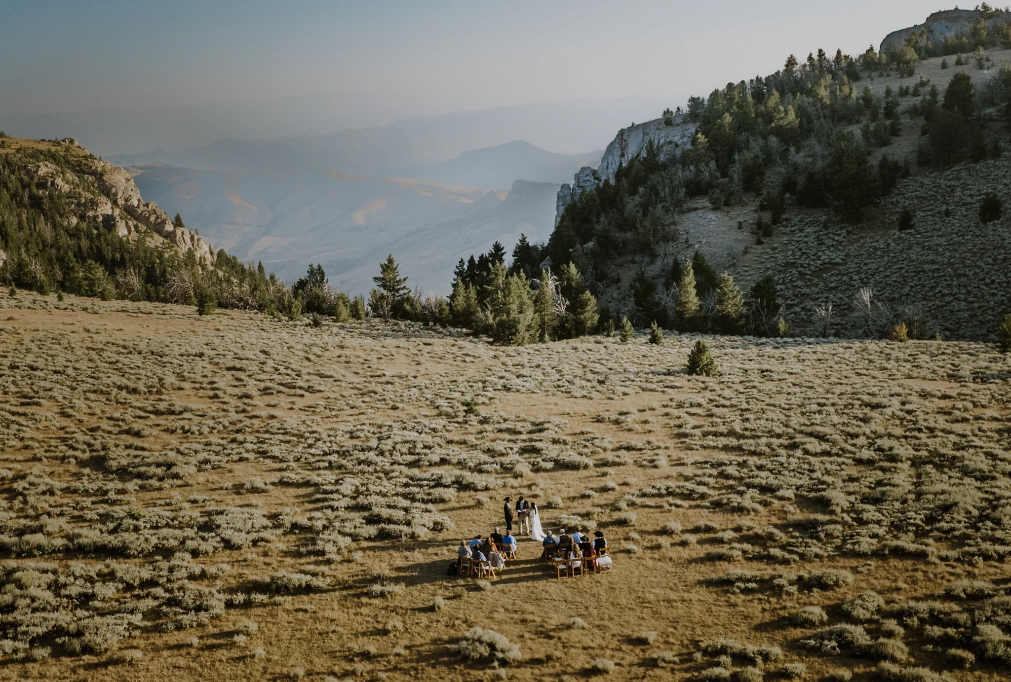 An intimate wedding ceremony among mountains and open meadow photographed from above
