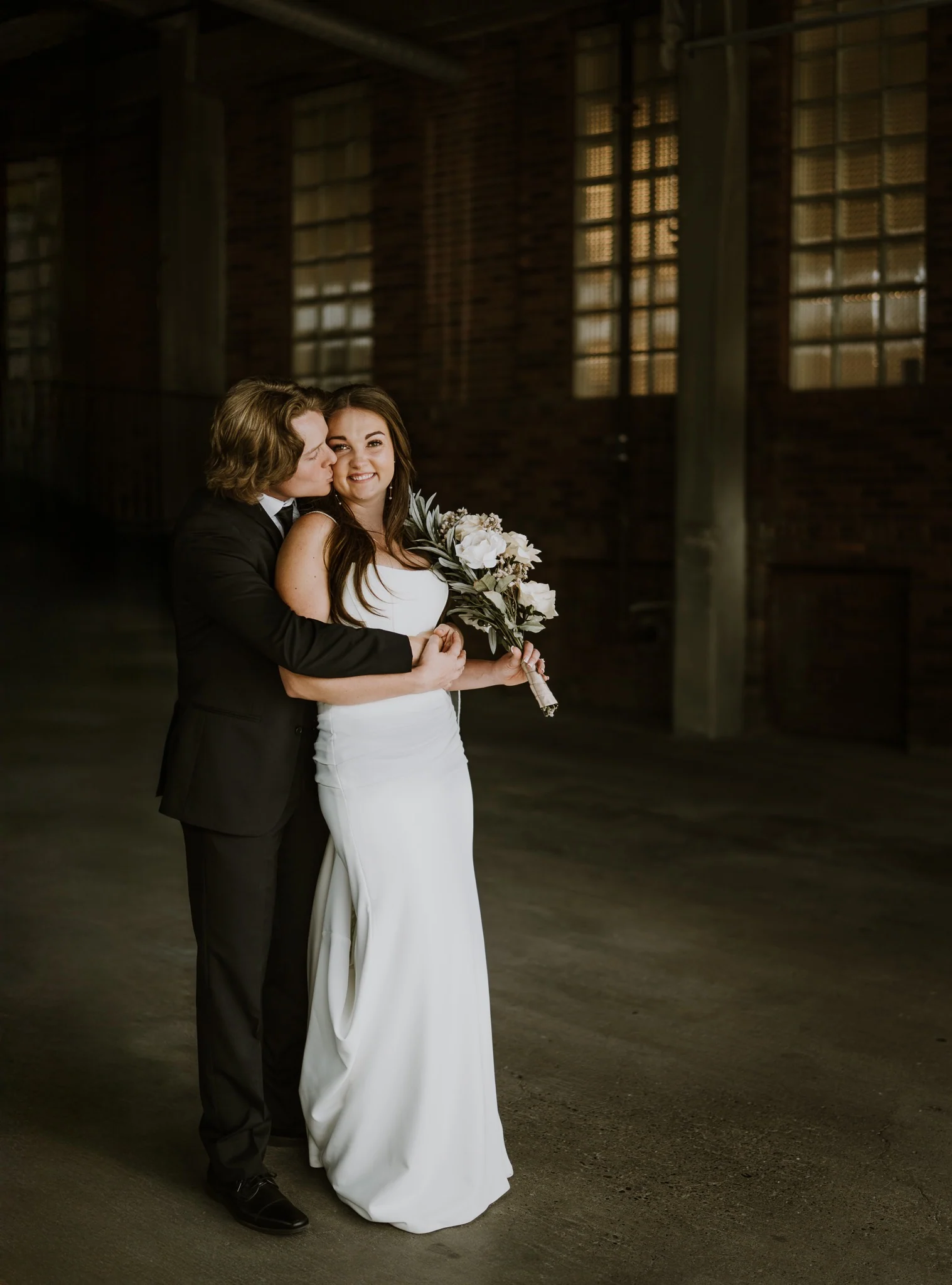 The newlyweds embracing in the softly lit reception venue