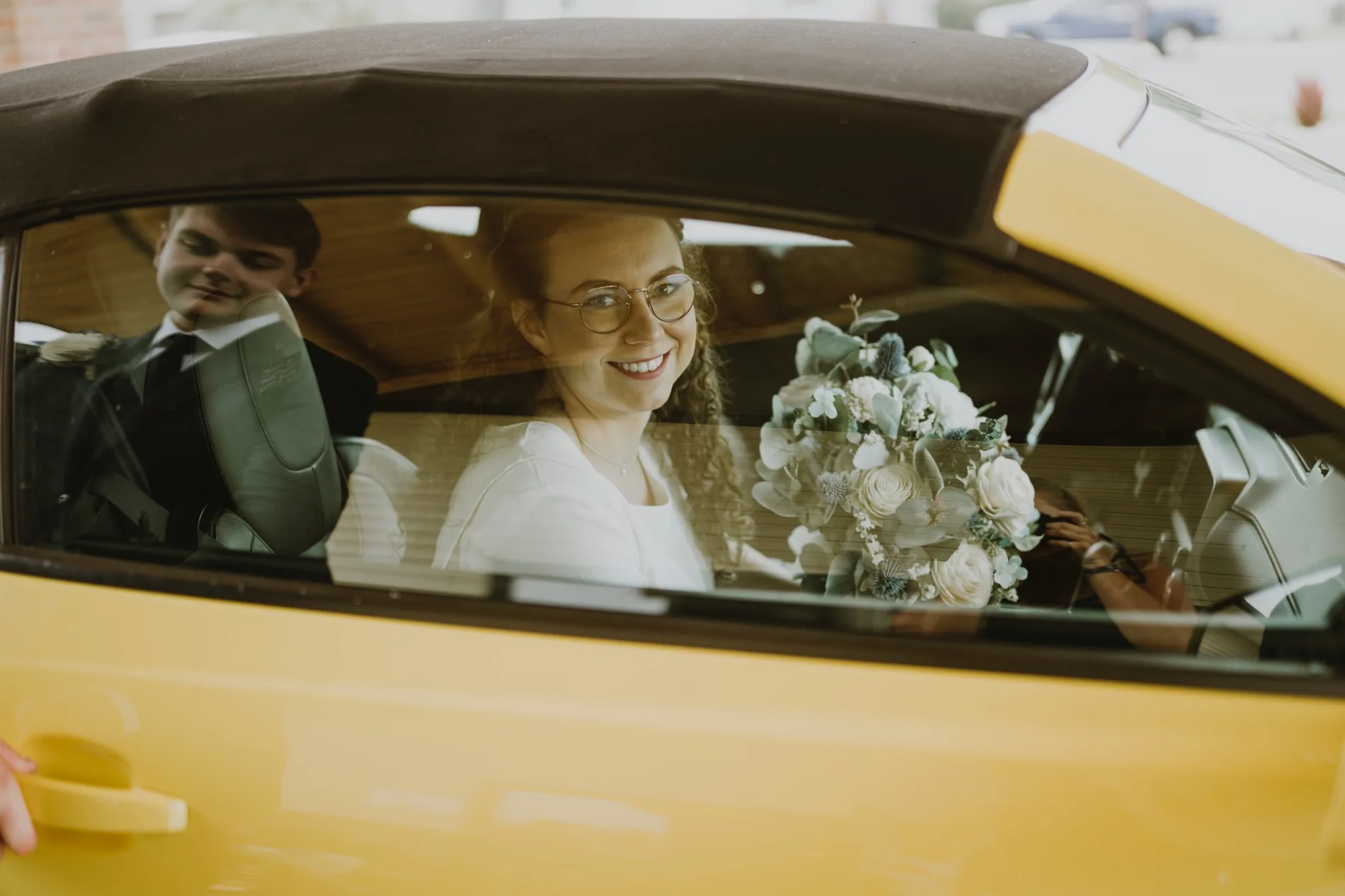 The wedding couple arriving together in a yellow car